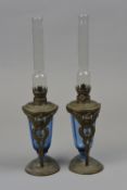 A PAIR OF ART DECO STYLE OIL LAMPS, with blue glass bodies in metal mounts consisting of a winged