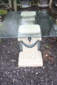 A GLASS TOPPED GARDEN TABLE, with two stone effect plastic column supports, 202cm x 116cm x 77cm