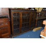 AN EARLY 20TH CENTURY CARVED OAK ASTRAGAL GLAZED THREE DOOR BOOKCASE, with adjustable shelving,