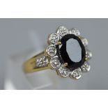 A MODERN SAPPHIRE AND DIAMOND OVAL CLUSTER RING, one oval mixed cut dark blue sapphire measuring