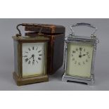 A BRASS CARRIAGE CLOCK, with it's travelling case and another carriage clock