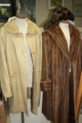 A LONG BROWN FUR COAT, together with a faux fur hat and a cream leather/sheepskin long coat (size M)