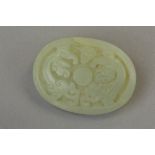 A PALE JADE OVAL PAPERWEIGHT CARVED WITH MYTHICAL CREATURE