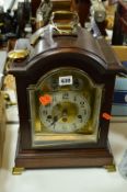 A CONTINENTAL MANTEL CLOCK, having arched brass dial with silvered chapter ring and Arabic numerals,