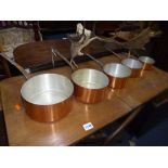 A SET OF FIVE COPPER GRADUATED PANS, with iron hooped handles