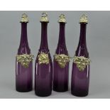 A SET OF FOUR AMETHYST COLOURED GLASS DECANTERS, with leaf shaped bottle labels, 'Rum', 'Whisky', '