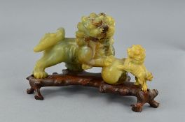 A CHINESE JADE CARVING OF TWO DOGS OF FO WITH FRONT PAWS RESTING ON A BALL, on a carved stand, s.d.,