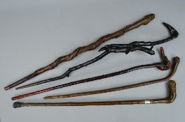 FIVE WALKING STICKS/CANES, including one with a silver collar, another fashioned as a face with