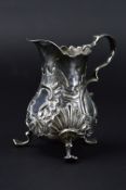 A GEORGE II SILVER CREAM JUG, of baluster form, wavy rim, 'S' scroll handle, repousse decorated with
