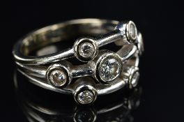 A MODERN 18CT GOLD DIAMOND SCATTER DESIGN RING, seven modern round brilliant cut diamonds rub over