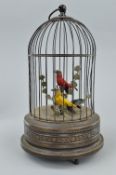 A 20TH CENTURY CLOCKWORK AUTOMATON OF TWO BIRDS IN A CAGE, both birds sing and move beaks, the red