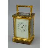AN EARLY 20TH CENTURY GILT BRASS CARRIAGE CLOCK, the handle, four columns, pediment and foot cast