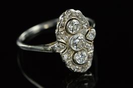 AN ART DECO OVAL CLUSTER RING, centring on three brilliant cut diamonds millegrain set, to a