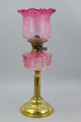 A LATE VICTORIAN/EDWARDIAN BRASS BASED OIL LAMP, the cranberry glass shade with acid etched floral