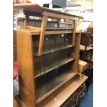 A LIGHT OAK ANGLED BOOKCASE WITHSLIDING GLASS DOORS, approximate width 91cm, a cantilever sewing box