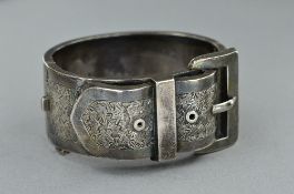 A LATE VICTORIAN SILVER BUCKLE BANGLE, wide hinged cuff design engraved in foliate decoration,
