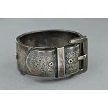 A LATE VICTORIAN SILVER BUCKLE BANGLE, wide hinged cuff design engraved in foliate decoration,