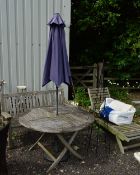 A ROUND TEAK GARDEN TABLE, with parasol, a teak garden bench, a metal vine frame and a teak garden
