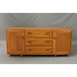 AN ERCOL GOLDEN DAWN ELM SIDEBOARD, flanked by three drawers central to two cupboard doors on