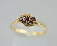 A 9CT THREE STONE CROSSOVER GARNET RING, ring size O, approximate weight 2.2 grams