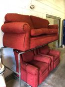 A RED UPHOLSTERED THREE PIECE LOUNGE SUITE, comprising of a three seater settee and a pair of