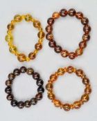 FOUR BURMESE AMBER BEAD BRACELETS, designed as expandable spherical bead bracelets, beads