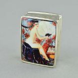 A SMALL ENAMEL PILL BOX, depicting a scantilly clad woman, stamped 'STERLING', approximate length