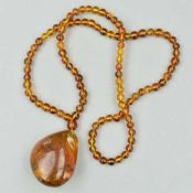 A BURMESE AMBER BEAD NECKLACE, with beaded amber neck chain and polished amber pendant drop with
