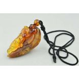 A CARVED BURMESE AMBER PENDANT, carved to depict a dragon with a cord chain, approximate length of