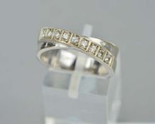 A DIAMOND HALF ETERNITY RING, of crossover design, one line claw set with modern round brilliant cut