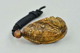 A CARVED BURMESE AMBER PENDANT, carved to depict a fish with cord chain, approximate length of