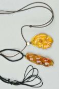 TWO CARVED BURMESE AMBER PENDANTS, the first carved to depict a flower, the second with fauna