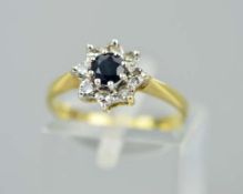 AN 18CT SAPPHIRE AND DIAMOND CLUSTER RING, the central circular sapphire within a single cut diamond