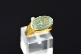 A ROMAN GOLD AND GREEN GLASS INTAGLIO SEAL RING, possibly 4th or 5th Century A.D., the oval intaglio