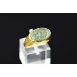 A ROMAN GOLD AND GREEN GLASS INTAGLIO SEAL RING, possibly 4th or 5th Century A.D., the oval intaglio