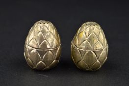 A PAIR OF 20TH CENTURY NOVELTY WHITE METAL PEPPERETTES, of ovoid form, pineapple style bodies,