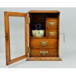 A LATE VICTORIAN OAK SMOKERS CABINET, glazed door enclosing an arrangement of four drawers with