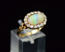 A LATE 19TH CENTURY OPAL AND DIAMOND OVAL CLUSTER RING, fancy scroll shoulders and open pierced