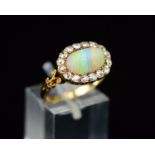 A LATE 19TH CENTURY OPAL AND DIAMOND OVAL CLUSTER RING, fancy scroll shoulders and open pierced