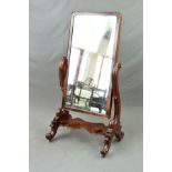 A MID VICTORIAN MAHOGANY CHEVAL MIRROR, of rectangular form, supported on a scrolled frame with dual
