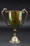 A GEORGE V SILVER TWIN HANDLED TROPHY CUP, bears presentation inscription, on a hexagonal pedestal