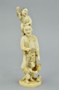 A LATE 19TH CENTURY JAPANESE IVORY OKIMONO, carved with a young boy holding a stick standing on a