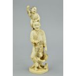 A LATE 19TH CENTURY JAPANESE IVORY OKIMONO, carved with a young boy holding a stick standing on a