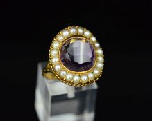 AN EARLY 20TH CENTURY SPLIT PEARL AND AMETHYST DRESS RING, centring on a round faceted amethyst,