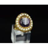 AN EARLY 20TH CENTURY SPLIT PEARL AND AMETHYST DRESS RING, centring on a round faceted amethyst,