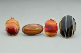 THREE AGATE PENDANTS AND AN AGATE BROOCH, all of oval outline, the brooch with silver mount