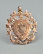 AN EARLY 20TH CENTURY ROSE GOLD CROWNED SHIELD FOB, with folIate decoration, measuring approximately
