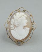 A CAMEO BROOCH, of oval outline depicting a female in profile, within an openwork scrolling and