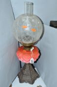 A LATE VICTORIAN OIL LAMP, acid etched glass shade, pink glass reservoir on a hexagonal cast iron