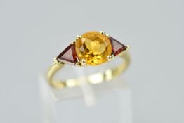A 9CT GOLD CITRINE AND GARNET RING, designed as a central circular citrine flanked by trianglur
